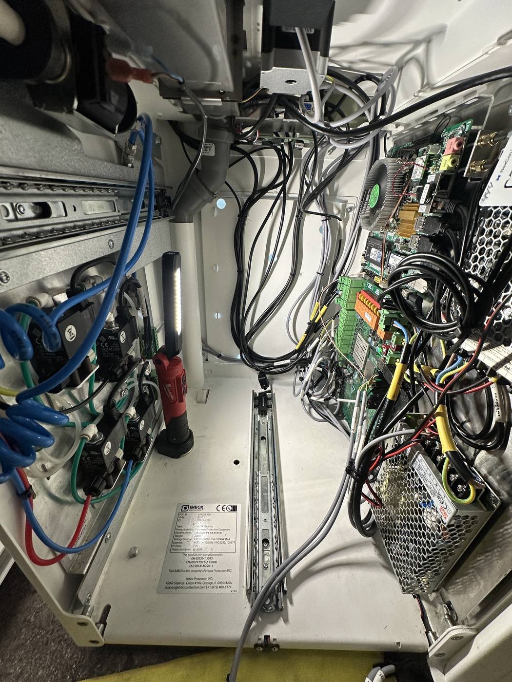 Open kiosk control panel showing the mainboard, USB peripherals, and cable harness